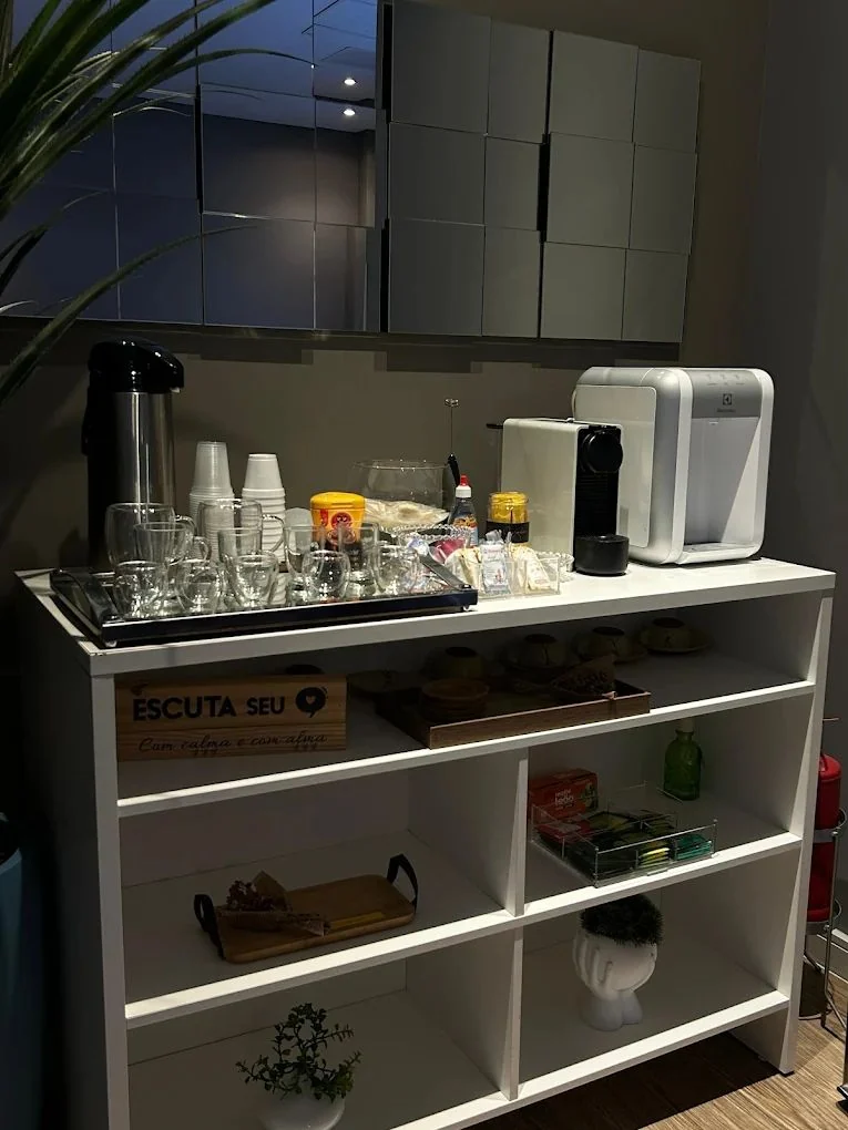 Canto do café da Clínica Vitessi com cafeteira, copos e plantas