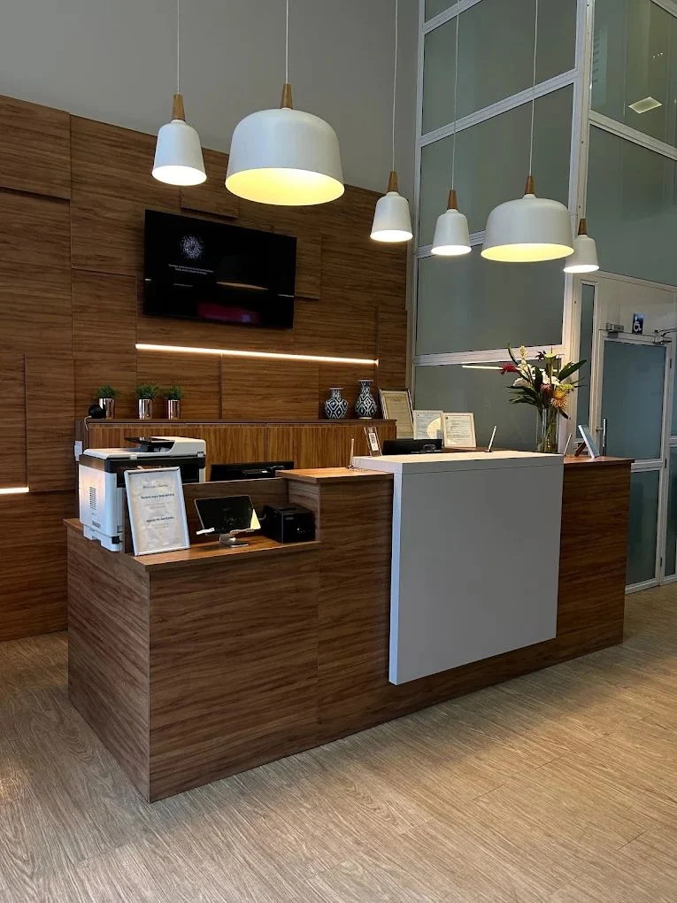 Balcão de recepção da Clínica Vitessi, com acabamento em madeira e luminárias pendentes